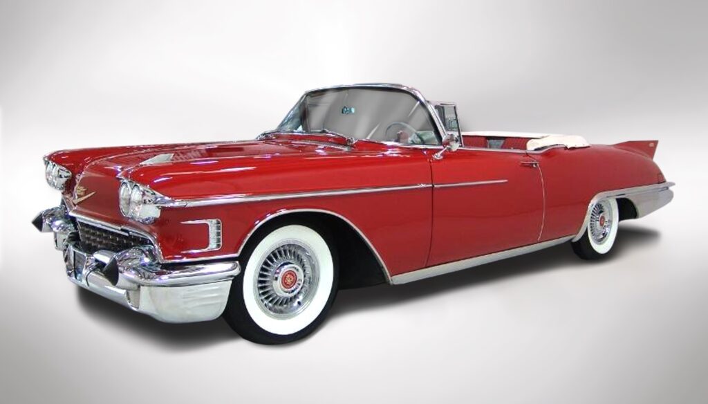 Classic red convertible car with whitewall tires and chrome details.
