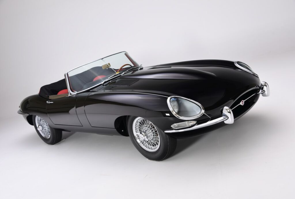 A sleek black vintage convertible car with chrome details and red interior.