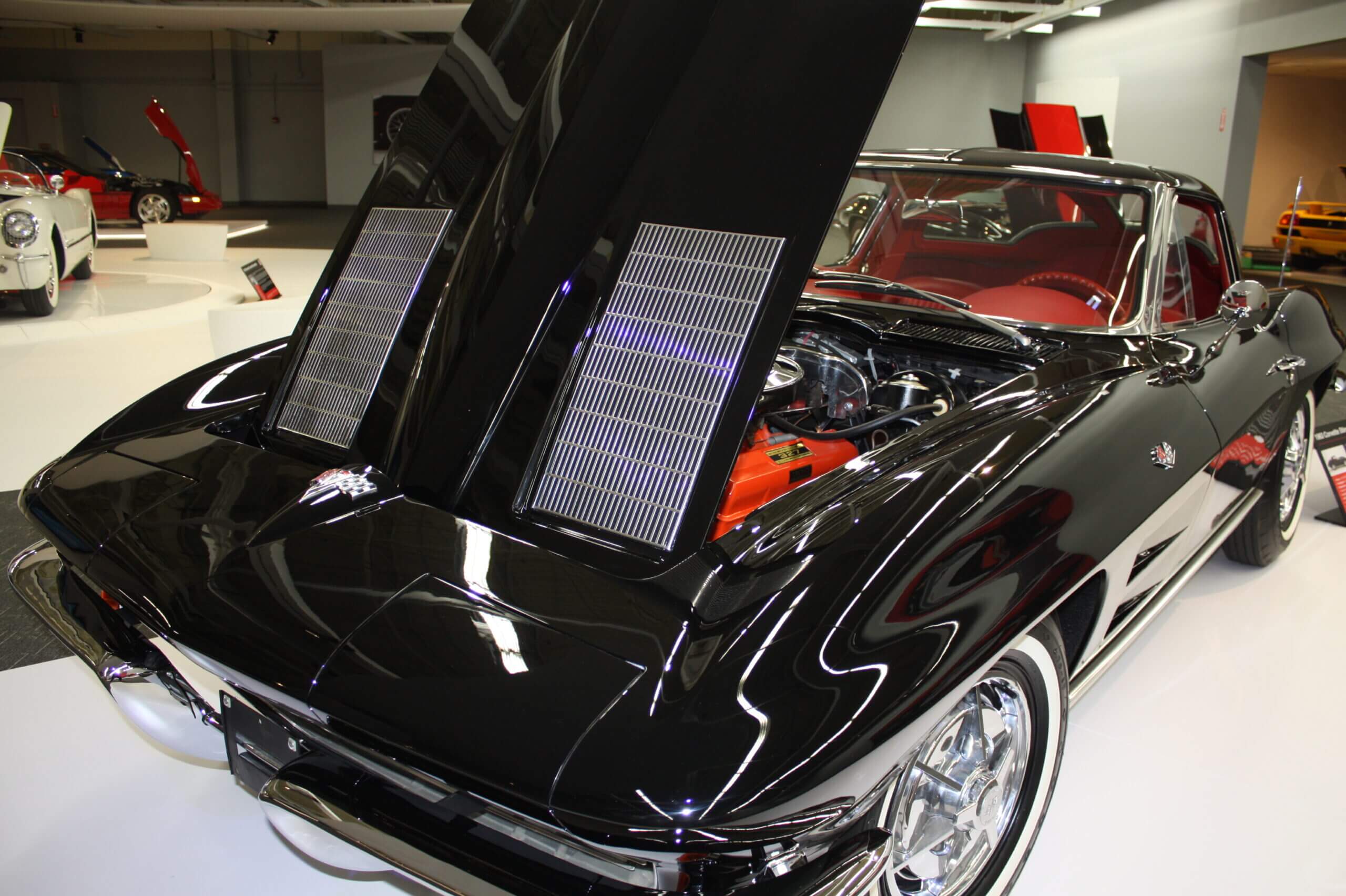Classic black car with its hood open, revealing a polished engine.
