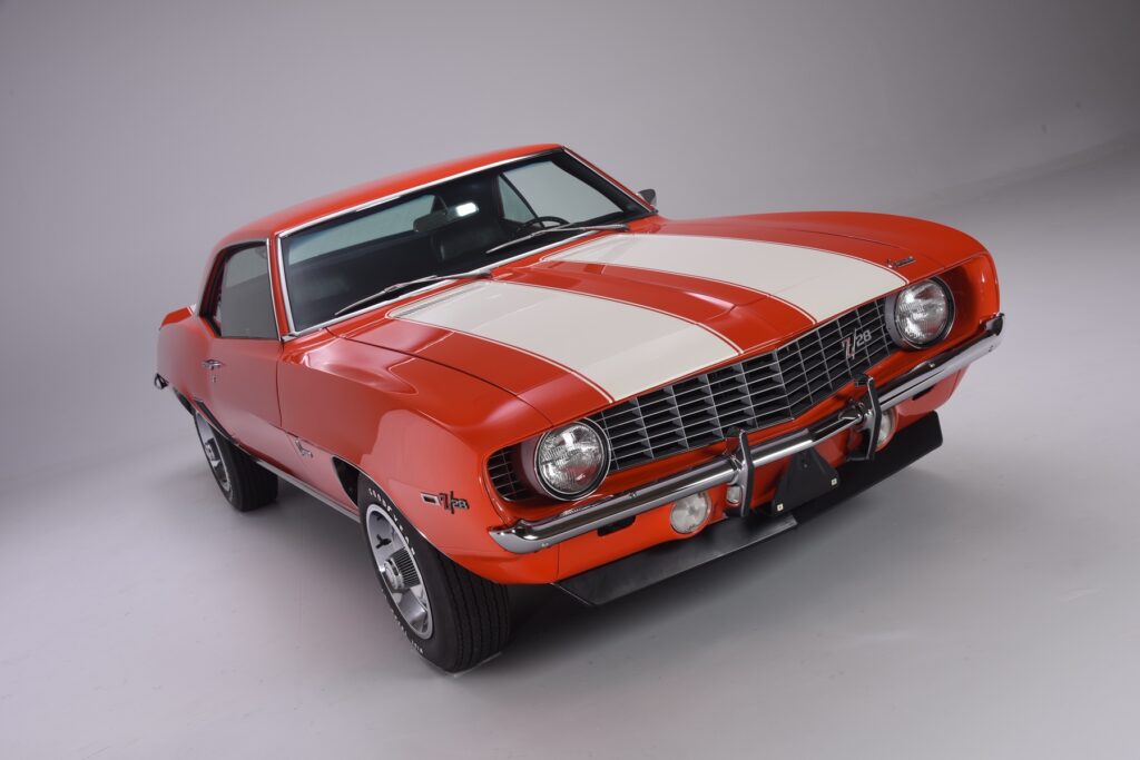 Red classic muscle car with white racing stripes.