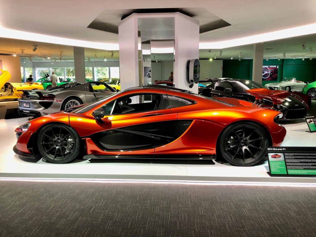 Sleek orange sports car on display under bright showroom lights.