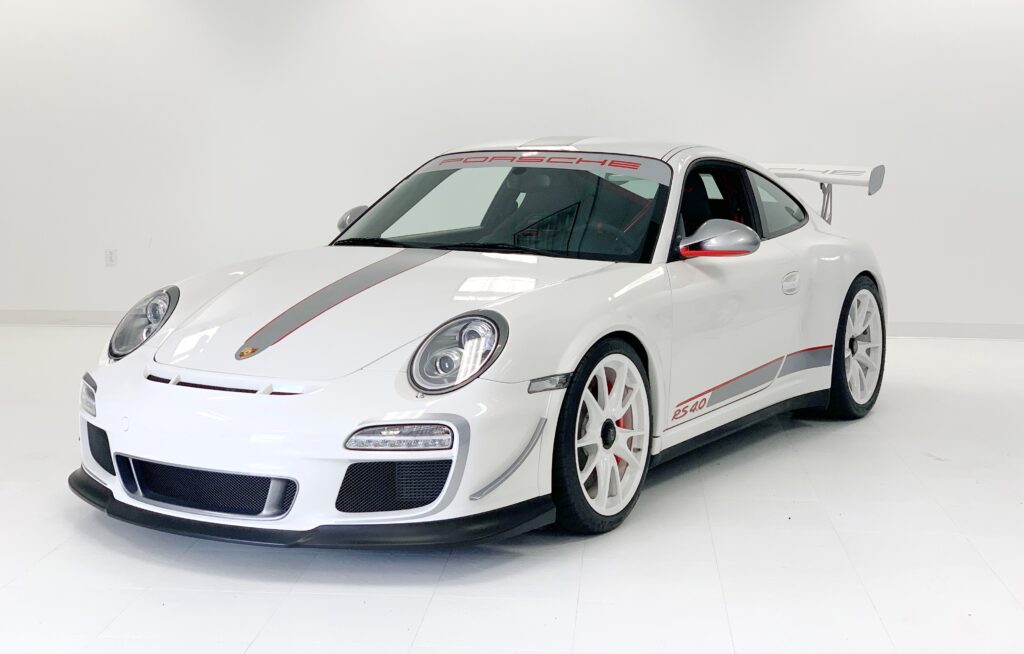 White Porsche sports car with racing stripes and red accents.