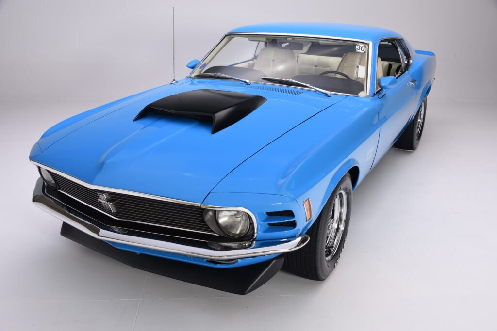 Blue classic Ford Mustang with black hood scoop and chrome detailing.
