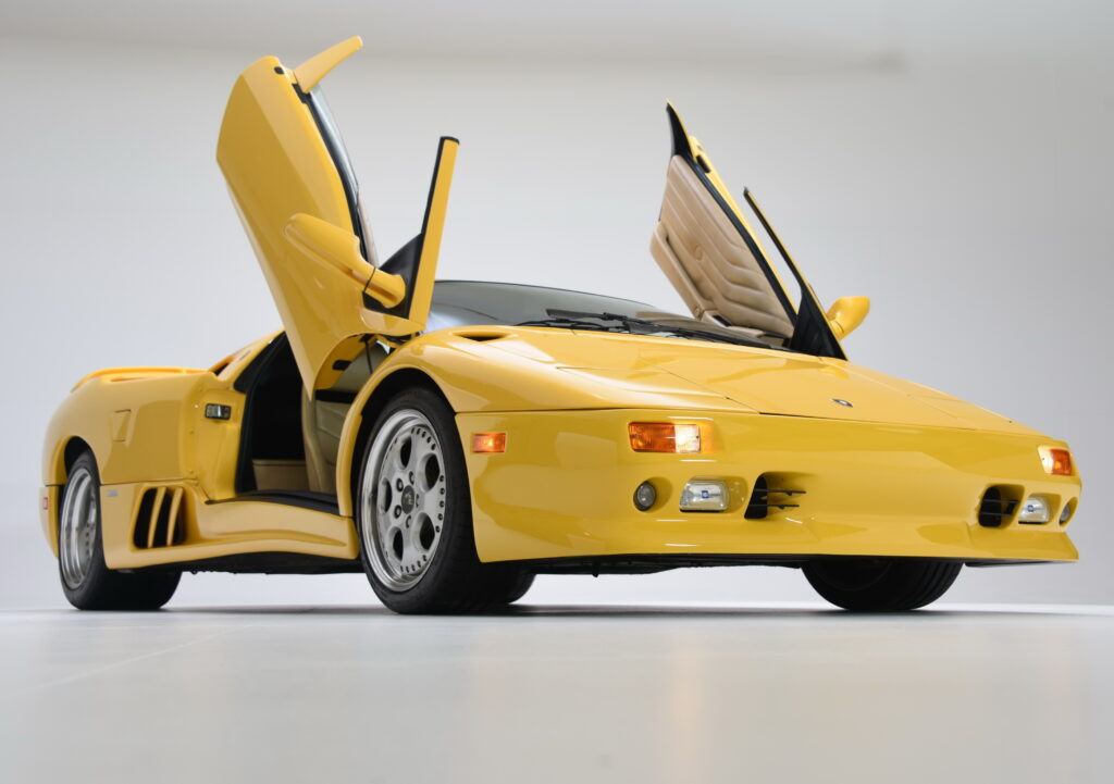 Yellow sports car with gull-wing doors open.