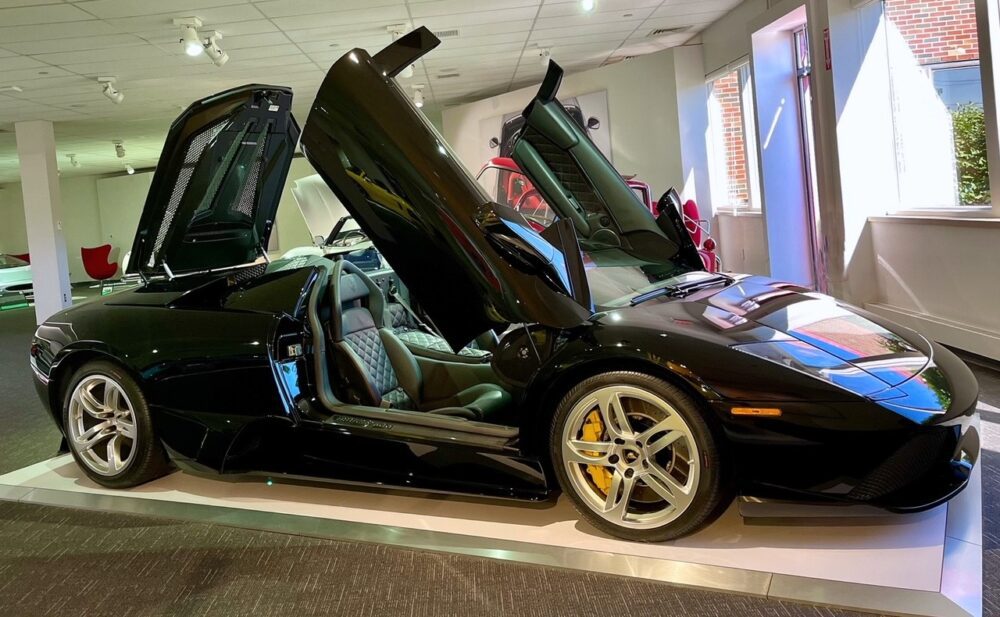 Black sports car with butterfly doors open indoors.