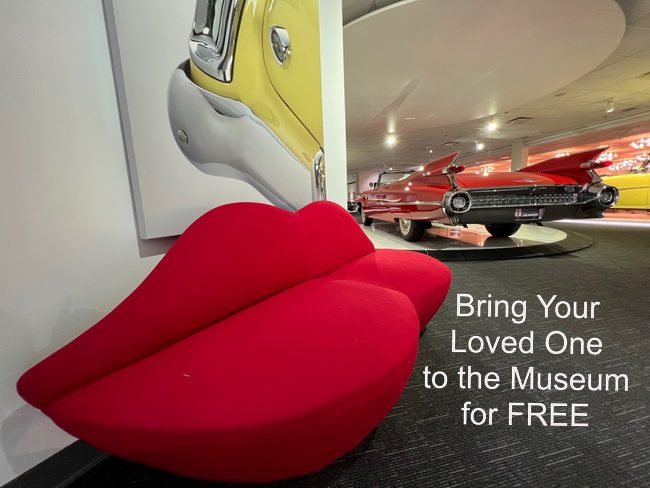 Bright red lips sculpture at a car museum entrance.
