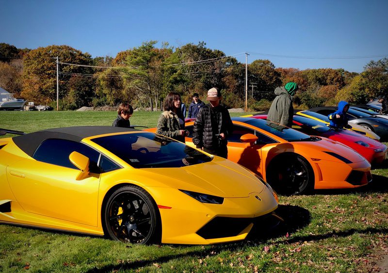 Two luxury sports cars parked outdoors with people nearby.