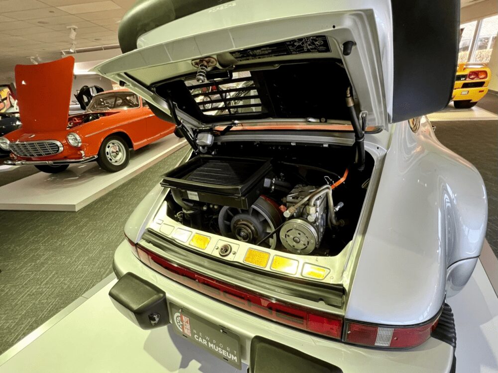Classic white Porsche 911 with engine exposed in a vintage car exhibit.