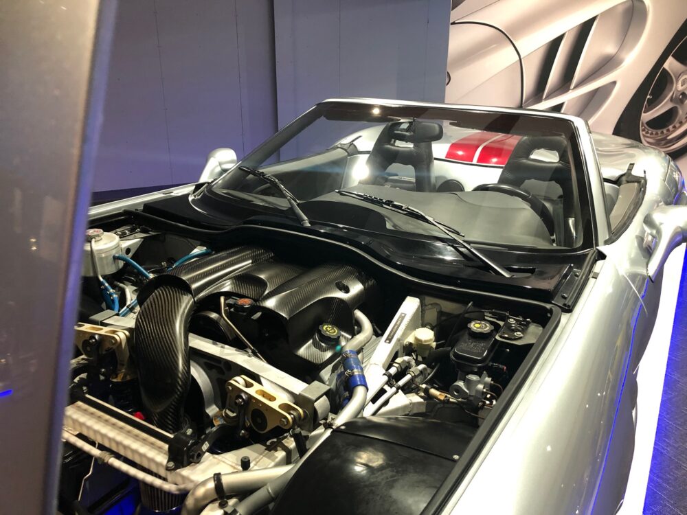 A car with its hood open showing engine components and modifications.