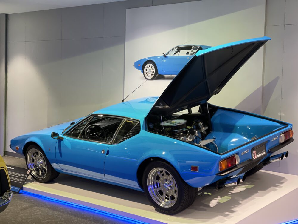 Classic blue sports car with an open engine compartment on display.
