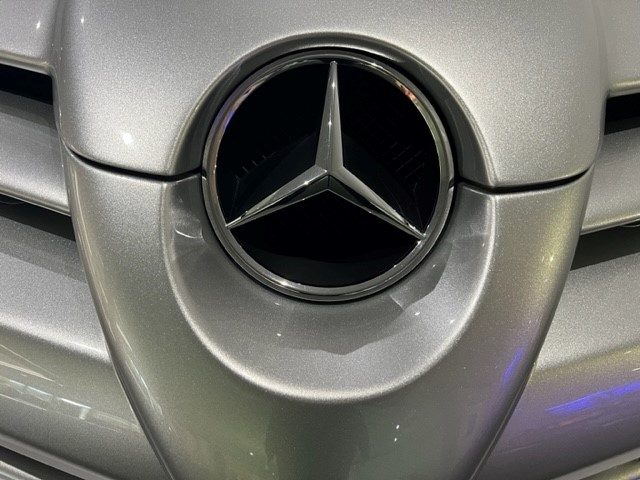 Close-up of a Mercedes-Benz logo on a silver car.