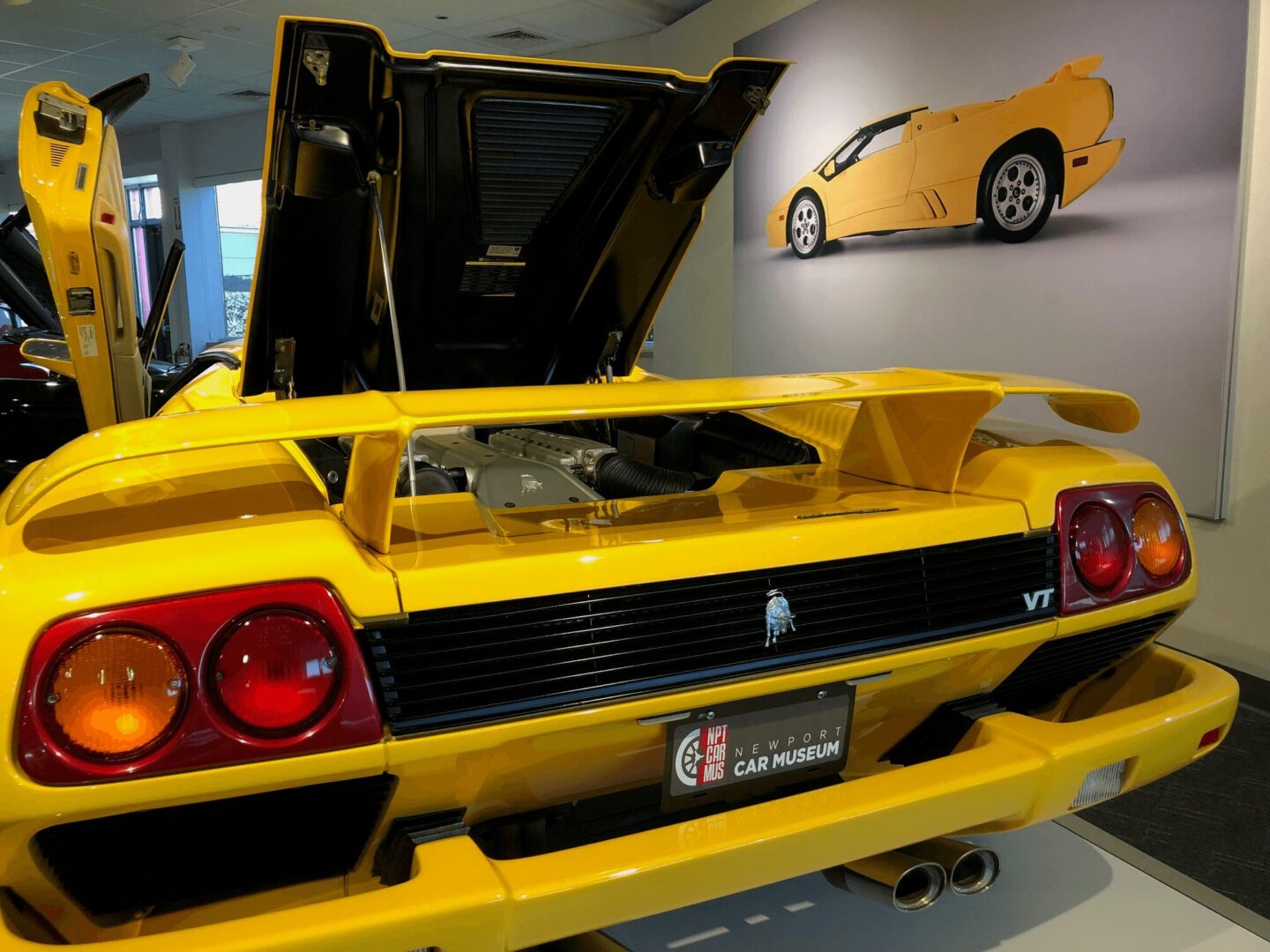 Yellow Lamborghini Diablo with open rear engine cover in a showroom.