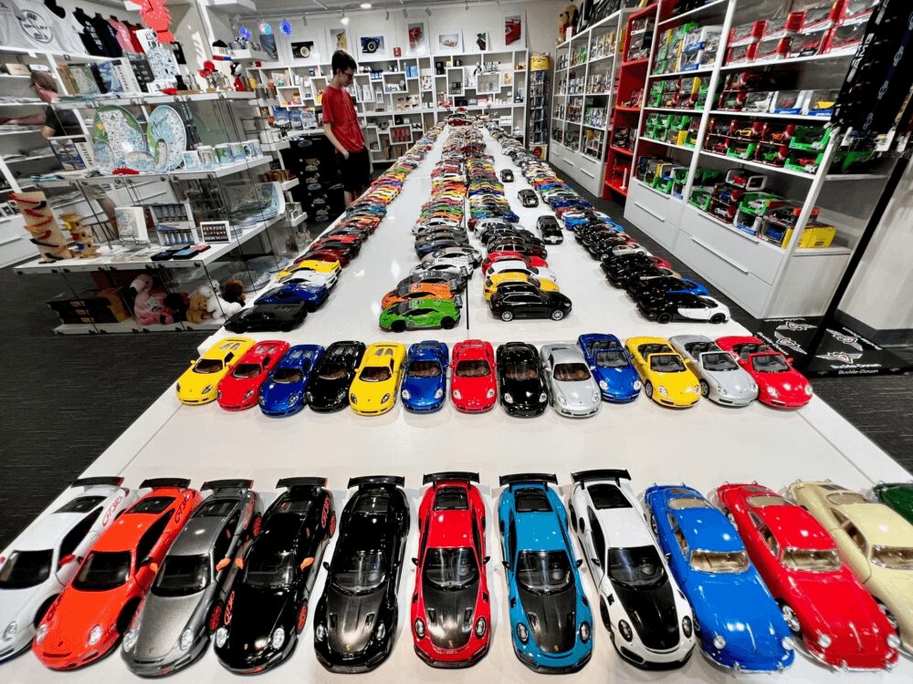 Rows of colorful toy cars displayed on a long table inside a store.