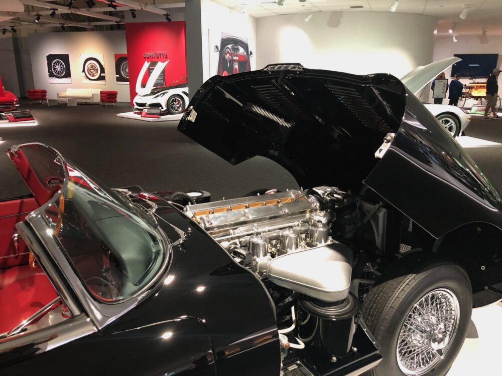Classic black car with its hood open, showcasing a highly polished engine.