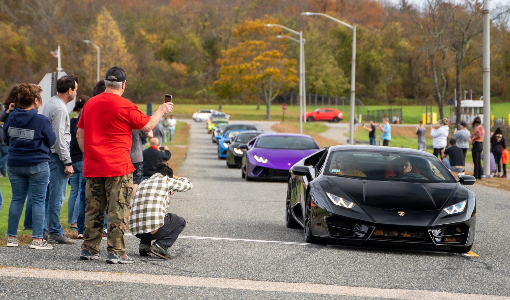 A lineup of luxury sports cars with photographers capturing the moment.