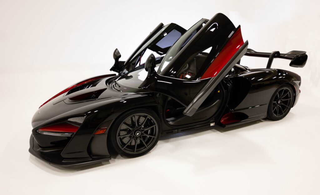 A sleek black sports car with butterfly doors open.