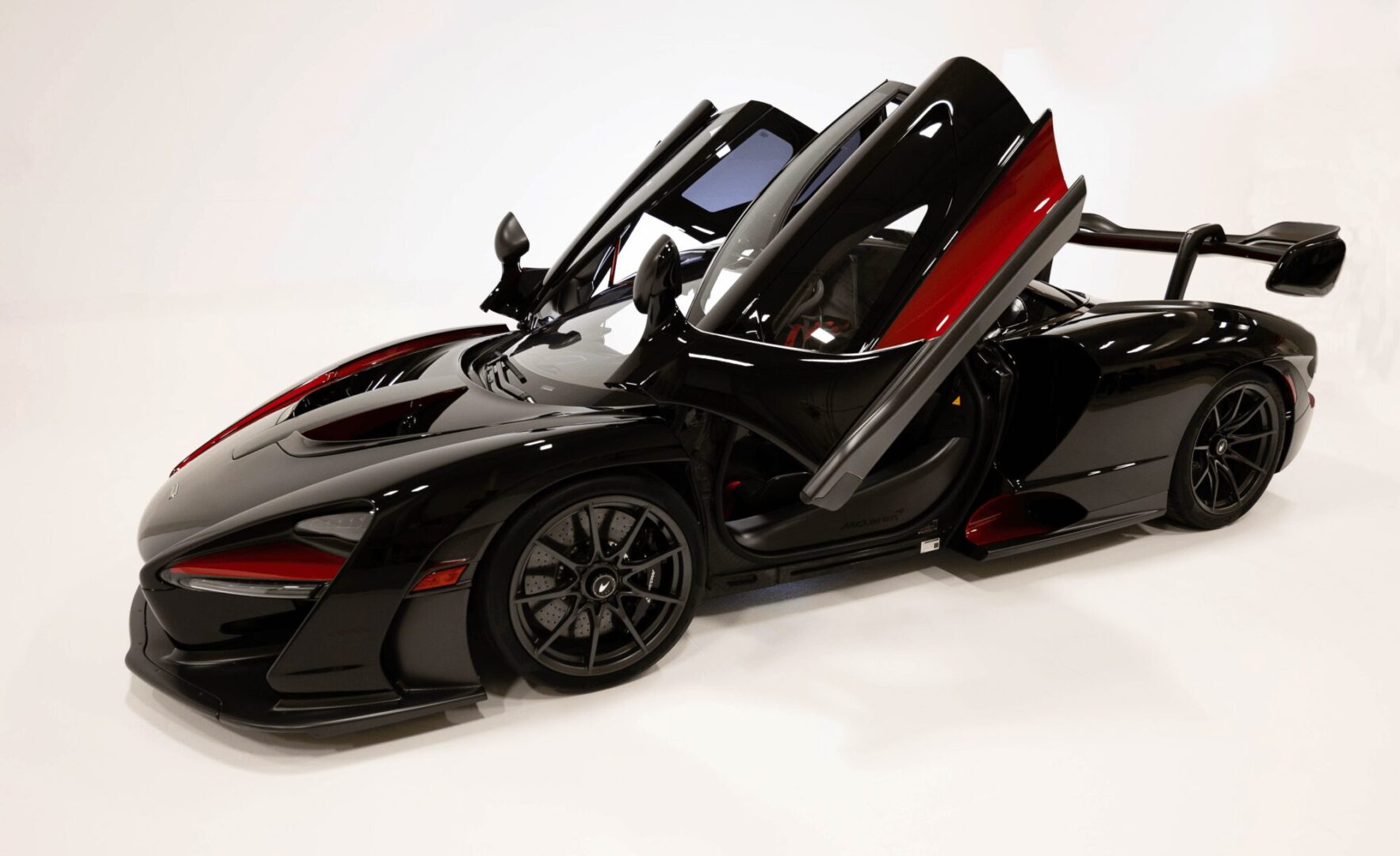 A sleek black sports car with butterfly doors open.