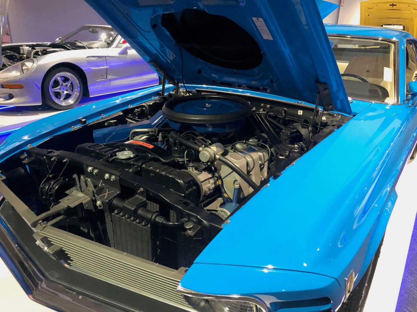Open hood of a blue classic car showing the engine.