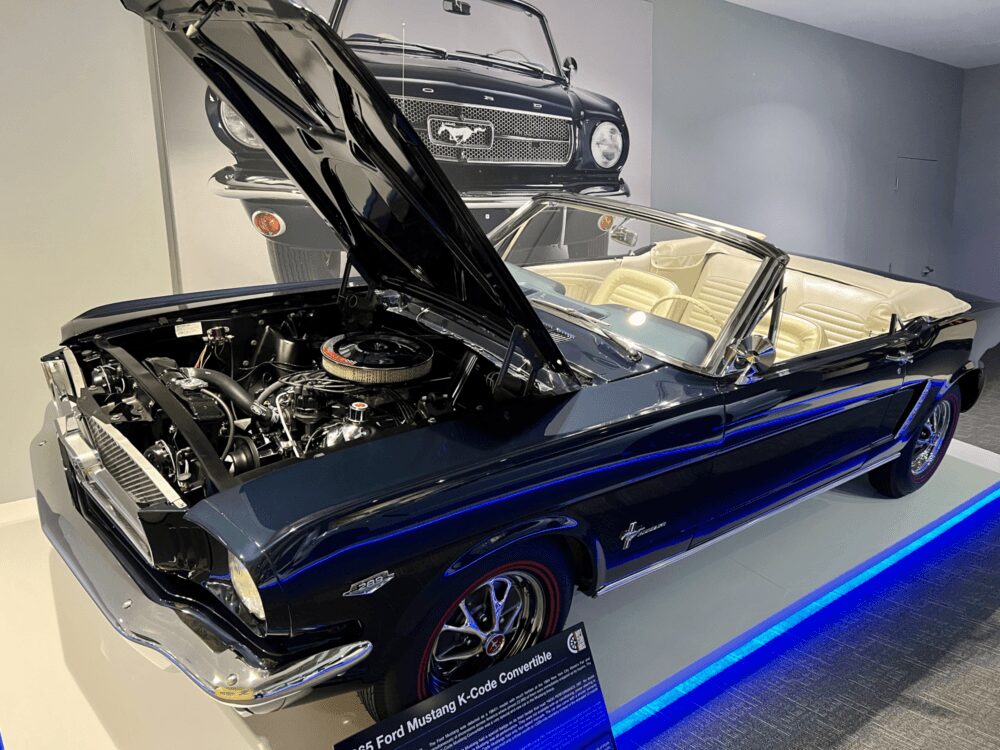 Classic blue Ford Mustang convertible with hood open, showcasing the engine.