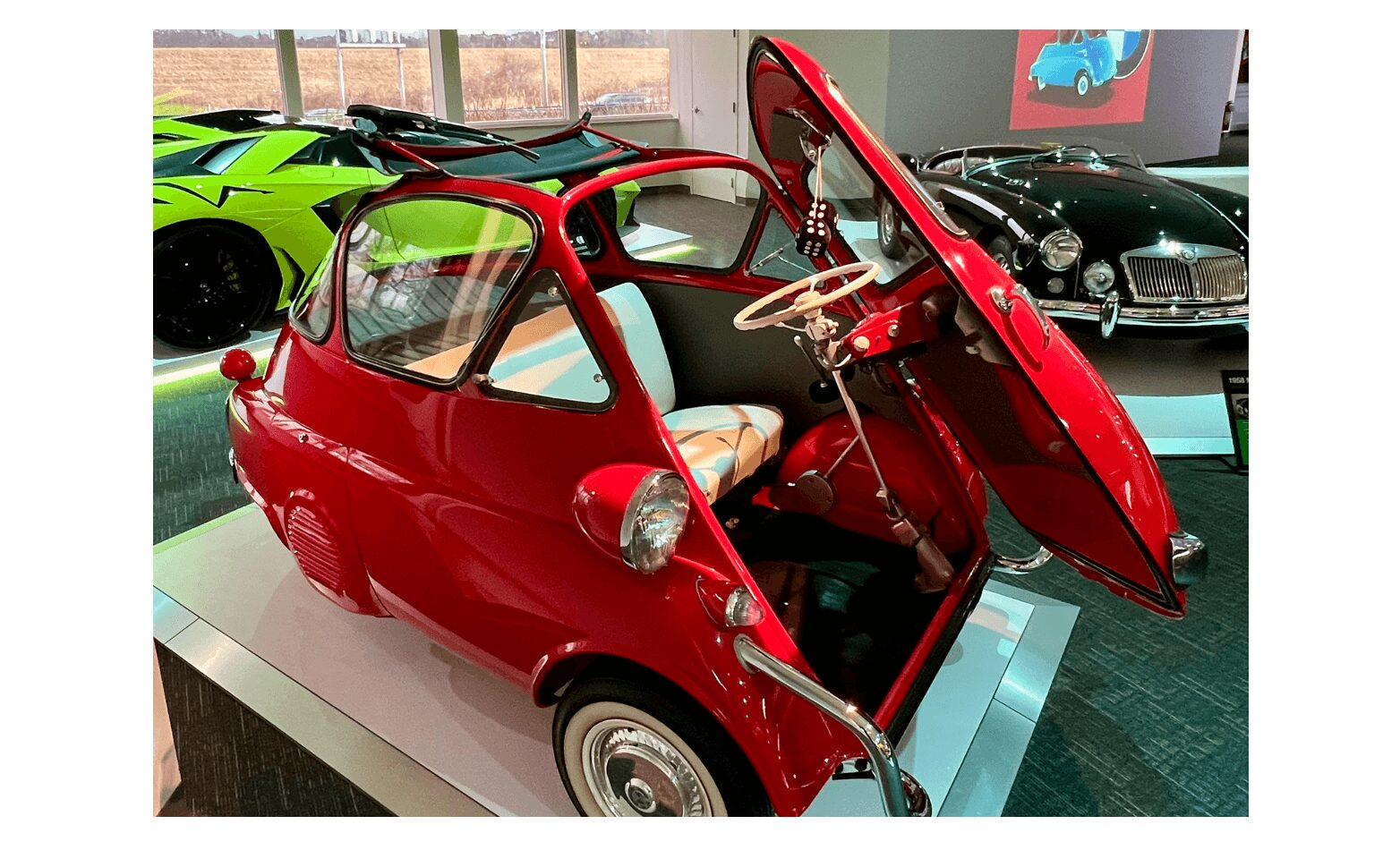 Red vintage microcar with butterfly doors on display indoors.