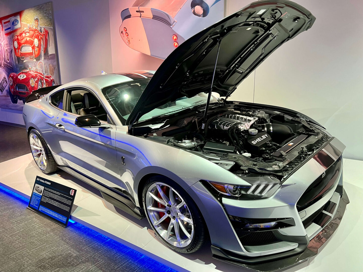 Shiny black sports car with hood open in showroom.