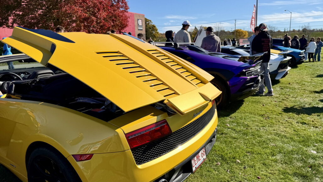 Yellow sports car with vents on the rear hood at a car show.