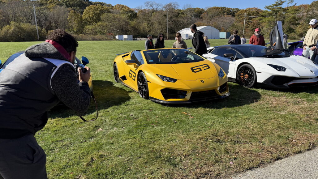 Yellow McLaren sports car displayed outdoors with people around.