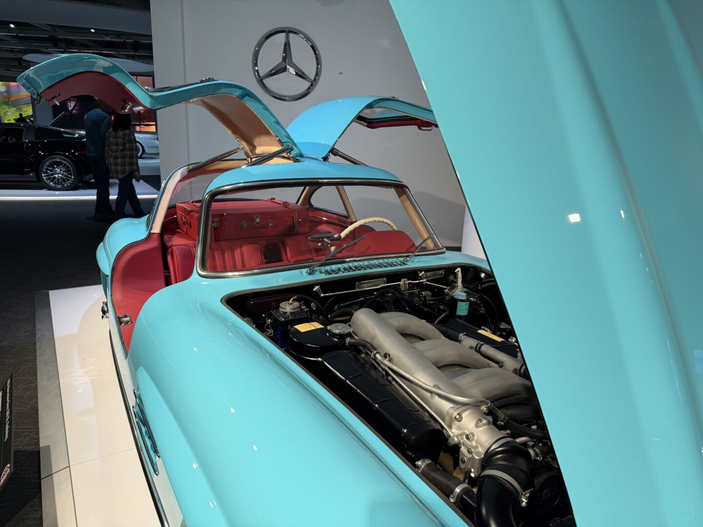 Vintage turquoise car with gullwing doors open.